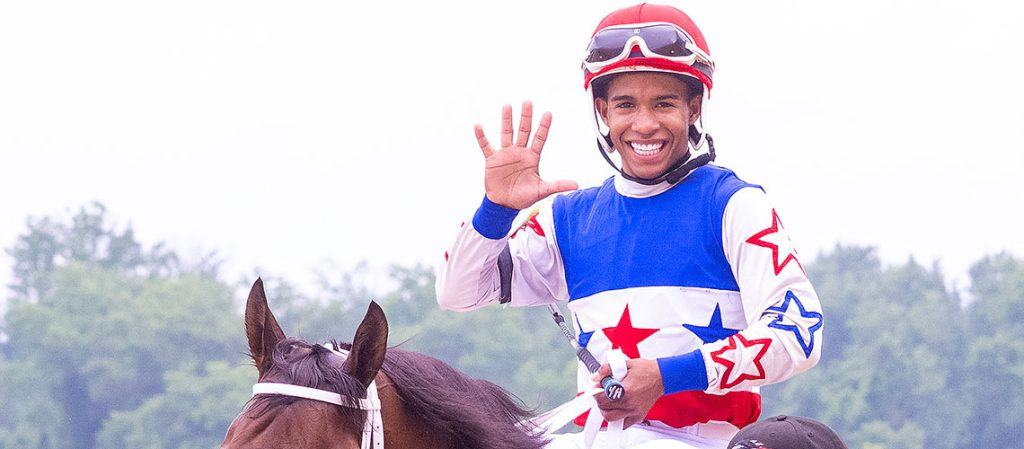 A jockey holds up five fingers after a win at Laurel Park